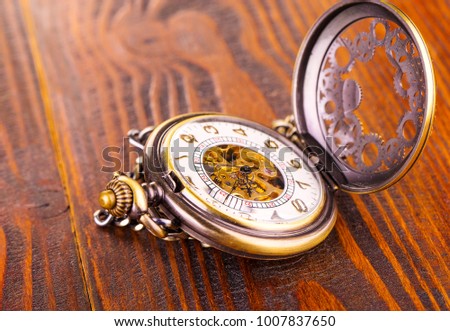 Image of an elegant antique pocket watch, photographed on an old wooden table