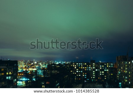 A view of the city's nightly bright city in lamps and lights with small clouds in the sky
