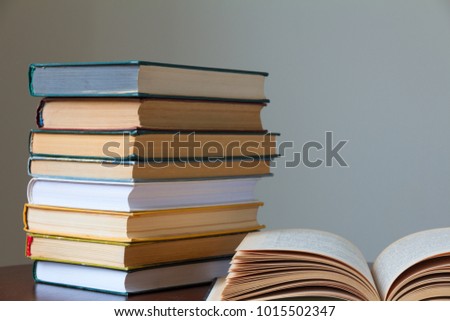 a stack of books on a wooden old table and a light background