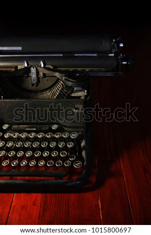 old vintage typewriter on a red stained hardwood floor with moody dramatic lighting 