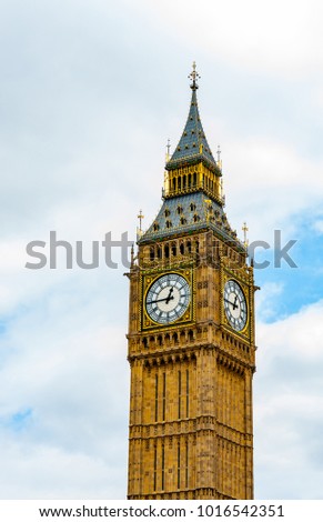 Big Ben clock tower in London, UK set against clouds in sky with copy space at top and side.