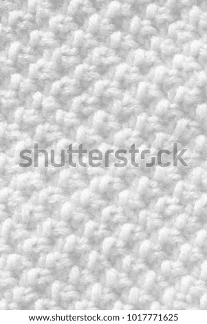 The knitted fabric is white. The texture of the woolen product is handmade.