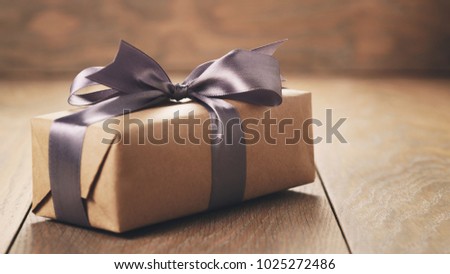 rustic craft paper gift box with lilac ribbon bow on wood table