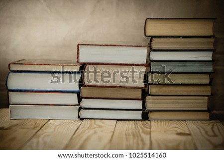 Textbooks and books on a wooden table. Book stack in the library room and blurred bookshelf for business and education background. 