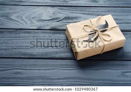 gift box wrapped in kraft paper with paper mustache on grey wooden background