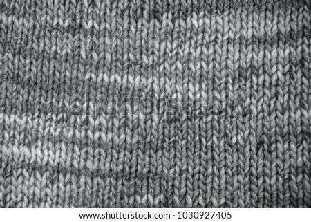 grey Wool scarf texture close up. Knitted jersey background with a relief pattern. Braids in machine knitting pattern