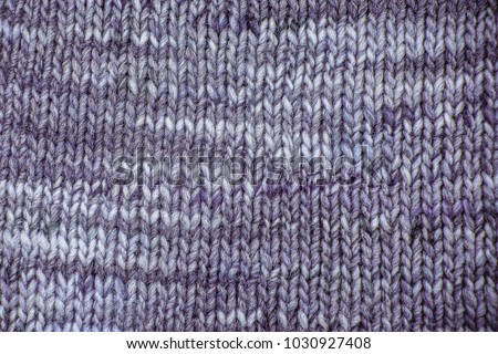 Purple Wool scarf texture close up. Knitted jersey background with a relief pattern. Braids in machine knitting pattern