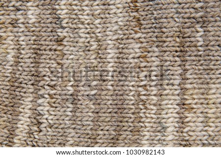 Wool scarf texture close up. Knitted jersey background with a relief pattern. Braids in machine knitting pattern