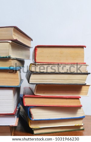 Stack of different old books on a table against a white wall background, reading concept