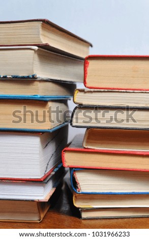 Stack of different old books on a table against a white wall background, reading concept