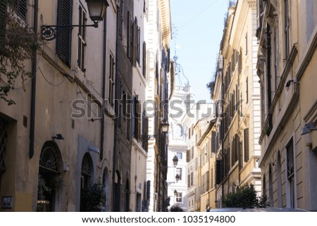  Narrow typical street with buildings lining both sides, clock tower in the background, stylized like retro vintage picture in Rome, Italy.