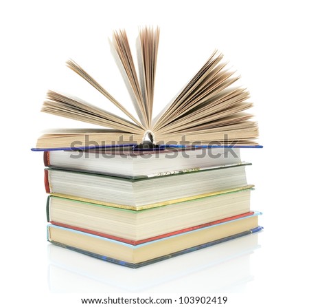 open book on a pile of books on a white background with reflection closeup
