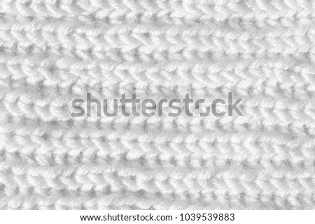 Knitting from woolen threads handmade. The texture is white, the background of the canvas is connected from the thread.