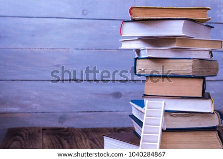 ladder on pile of old books on wooden background