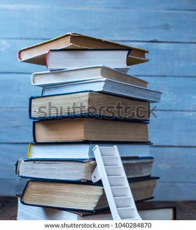 a ladder on pile of old books on wooden background