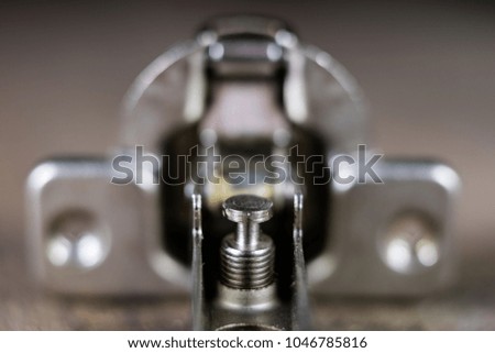 A woodwork hinge on a wooden workshop table. Joinery accessories for the construction of furniture in a carpentry workshop. Black background.