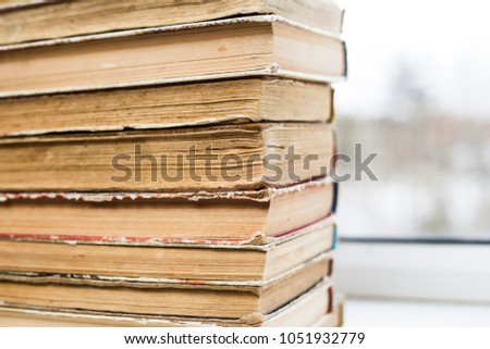 Old worn brown books in a pile, light background.