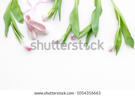 Ballet shoes near delicate flowers on white background top view copy space