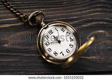 Gold vintage pocket watch on a wooden table. Old time background