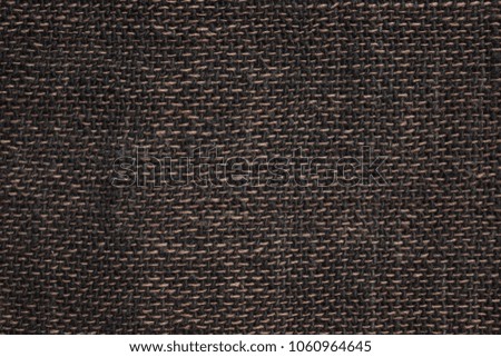 The texture of rough matting, linen fabric, home weaving. Large weaving, black and brown threads. A plain background without a pattern.
