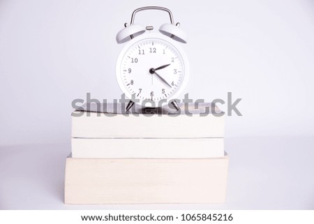 clock standing on the books on a white background.