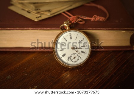 Antique vintage pocket watch on wooden table,background with old book
