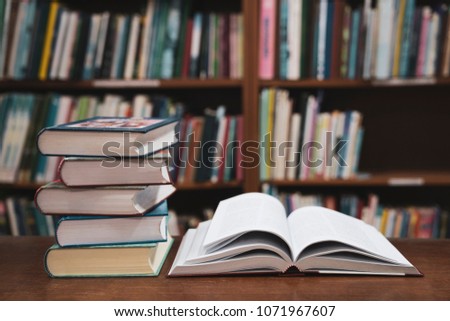 Open book on wood desk in the library room, Book stack in the library room and blurred bookshelf for business and education background, Back to school concept