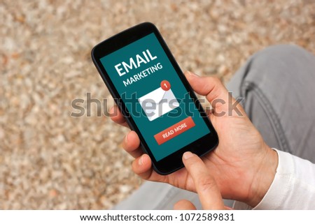Hands holding smart phone with email marketing concept on screen. All screen content is designed by me
