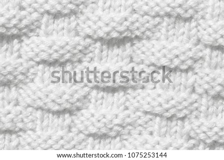 The texture of the knitted woolen cloth is white. Background for wallpaper or screen saver for the holiday.