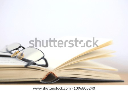 Close-up image of a book opened with glasses placed on a white background selective focus and with a very shallow depth of field
