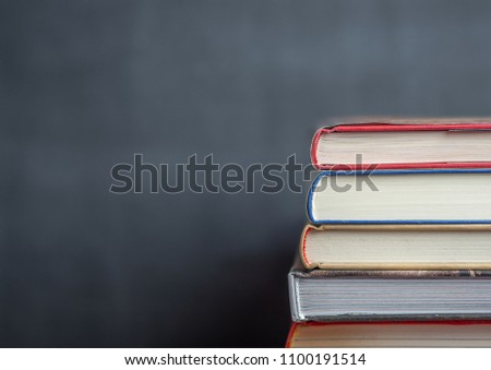 Stack of book resting in front of a chalkboard with the books in focus