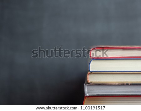 Stack of book resting in front of a chalkboard with the books in focus