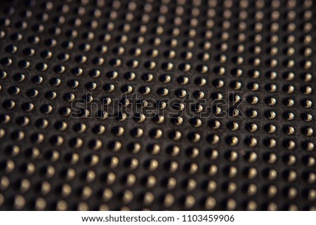 Black golden dotted texturised technological seamless fabric or surface closeup