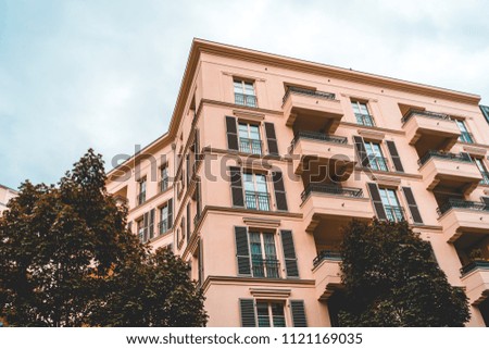 orange apartment building with green trees and cloudy sky