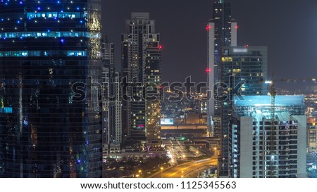 Dubai business bay towers aerial night timelapse. Rooftop view of some illuminated skyscrapers and new towers under construction. Traffic on the road
