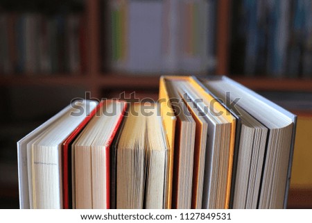 Books stacked in the library have bookshelves in the background selective focus and shallow depth of field