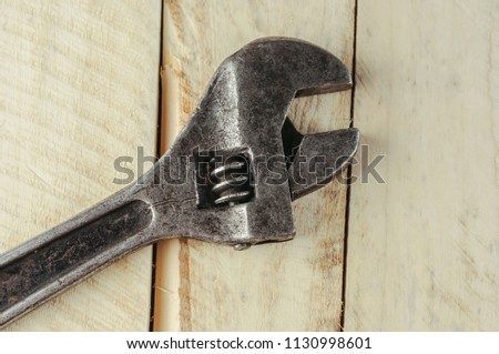 Old adjustable wrench on a wooden background.