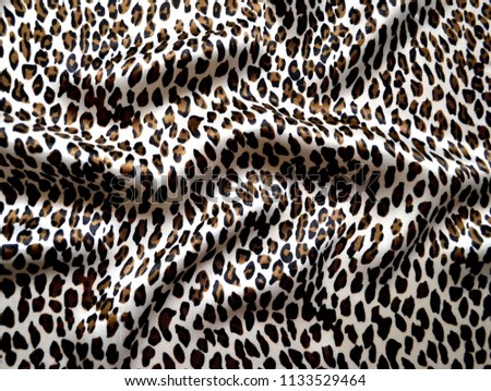 Photo of multi-colored silk fabric. Bright silk scarf with leopard print. Textile design.