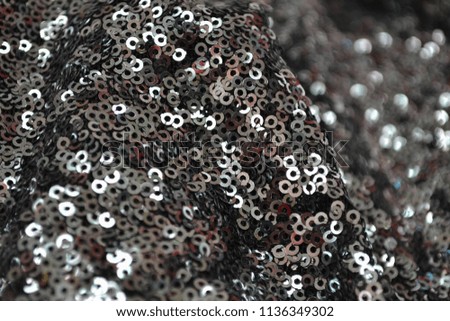 Pieces of cloth with silver sequins. Table in clothes workshop. Glitter background. Gray glitter background fabric texture. Glitter fabric. Sequin texture.