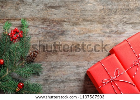 Beautiful gift boxes and fir tree branch on wooden background, top view