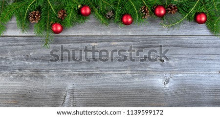 Overhead view of real fir Christmas tree branches and red ornaments on weathered wood  