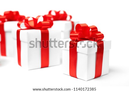 White gift box with red ribbon bow and christmas balls around, isolated on white background