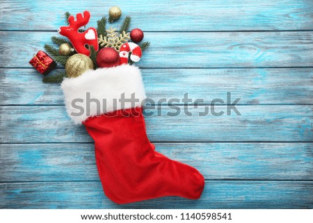 Red stocking with fir-tree branches and christmas decorations on wooden table
