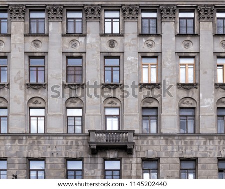 Vintage architecture classical facade old gray building front view. A multi-storey apartment house of the 19th century with antique motifs in decoration.
