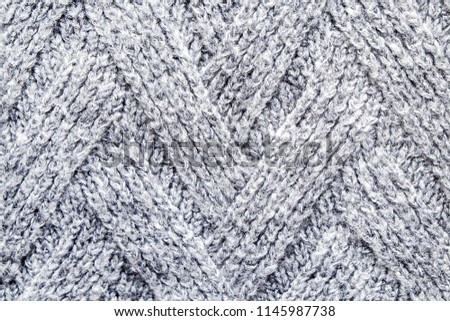 Cropped close up shot of seamless woolen knitting pattern of fall / winter season warm sweater, clearly visible fiber texture of stylish hipster knitwear clothing. Background, copy space, top view.
