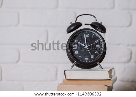 Alarm clock on wooden table on blackboard background