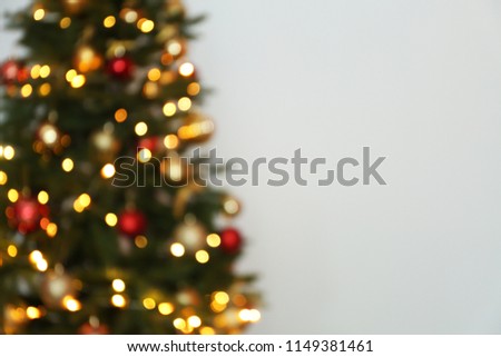 Blurred view of Christmas tree with fairy lights on white background