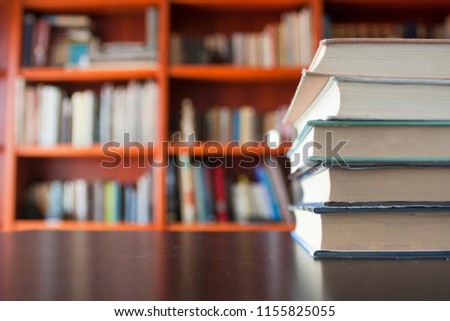 a bunch of books on the desk in front of the red library