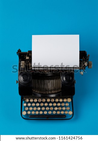 Vintage typewriter top down flatlay shot from above with empty, blank sheet of paper on cyan background