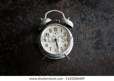 Old alarm clock on the ancient iron table in the concept of time and struggle.